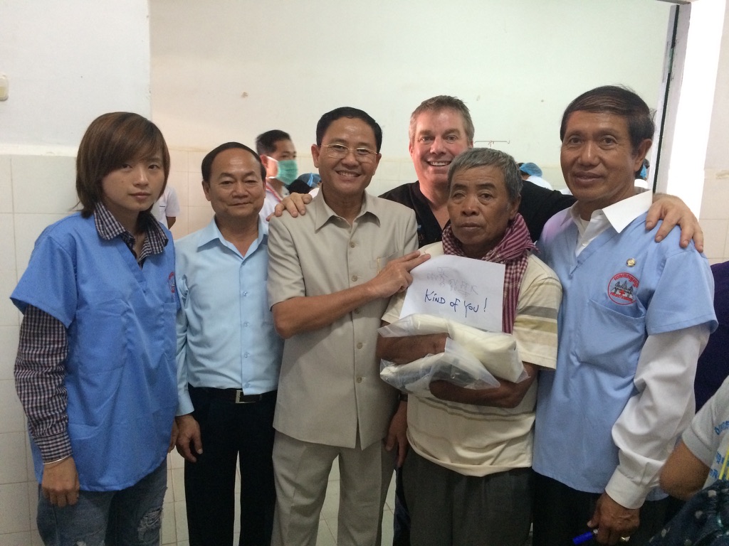 Steve Bender and the Cambodia team stand with a smiling hand recipient who holds his handwritten note reading Kind of you